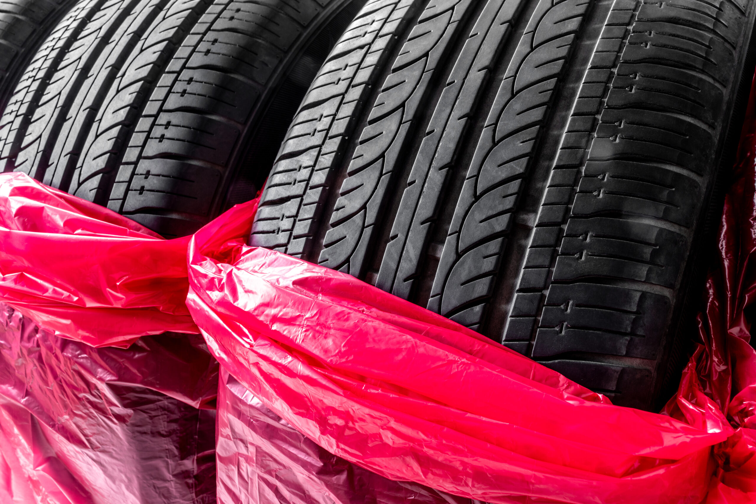 Zbliżenie na ustawione pionowo opony zapakowane w czerwone worki na koła - sklep.grala.com.pl